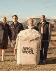 Four Wise Wool Employees on a Farm With a Big Bag of Wise Wool in Front of Them