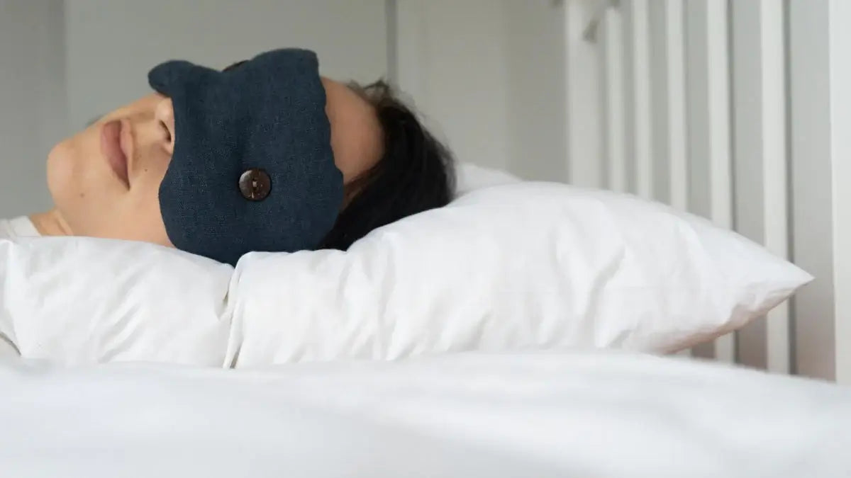 Picture of a young lady wearing the original Kind Face weighted eye mask and sleeping on the original Wisewool pillow