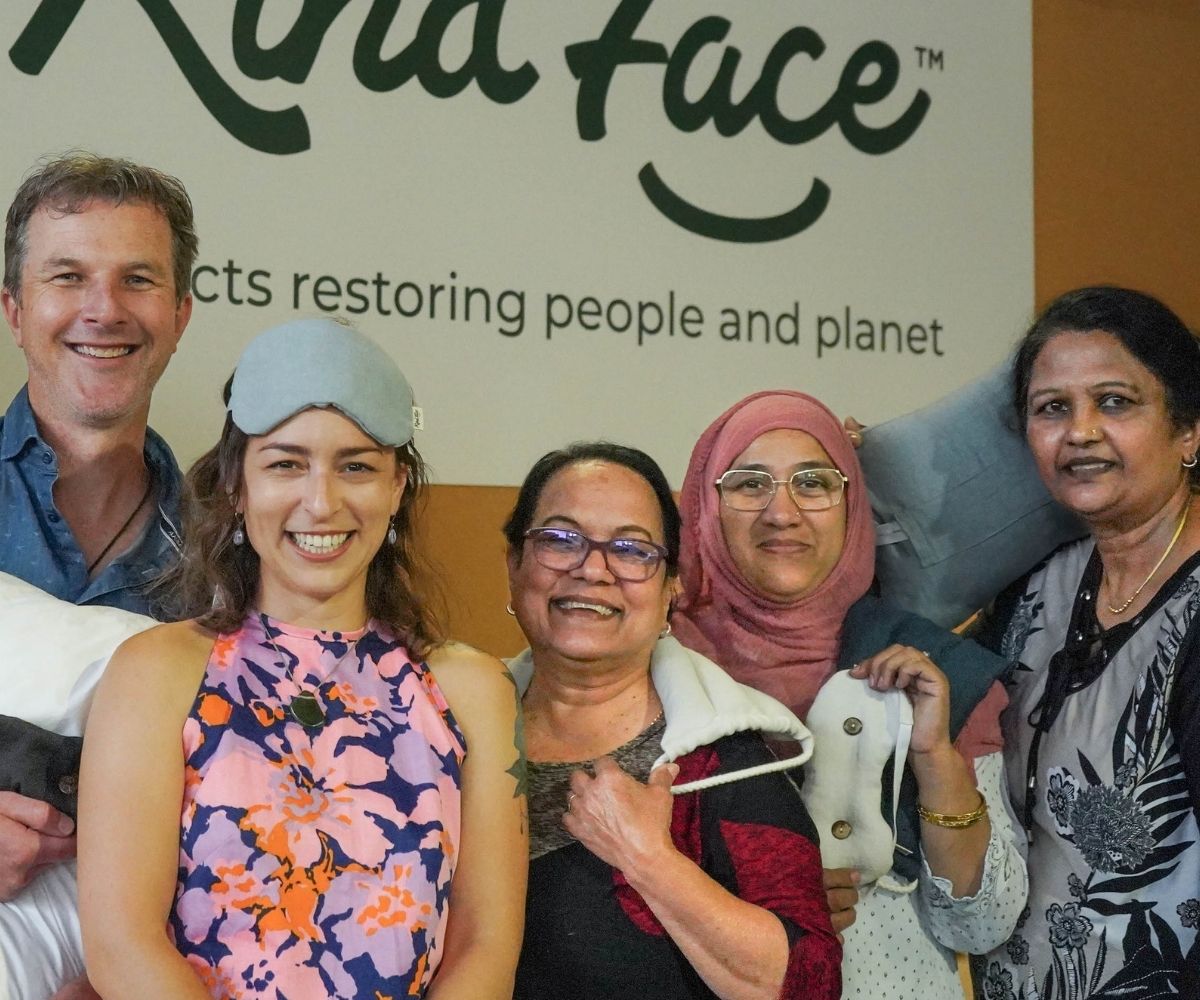 The workroom team posing together with a 'Kind Face' sign in the background